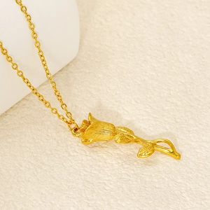 Collier élégant en acier inoxydable doré avec pendentif rose sur tissu beige