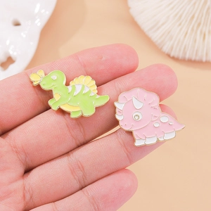 Cute cartoon dinosaur enamel pins in green and pink colors on a shell background