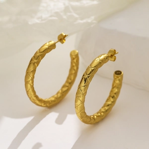 Detailed view of golden hoop earrings with classic quilted texture and polished finish