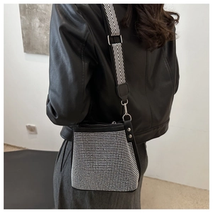 Detail of black rhinestone bucket bag featuring a textured herringbone wide shoulder strap
