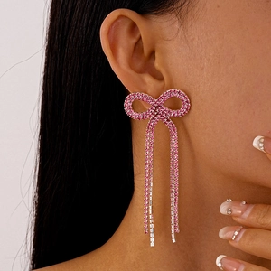 Détail de boucles d'oreilles nœud rose avec pampilles portées par un mannequin chic