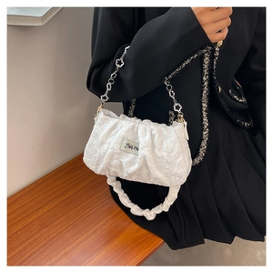 Detail of white pleated cloud bag featuring elegant metal chain and gathered shoulder strap