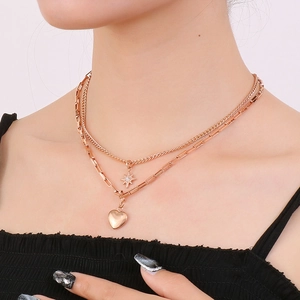 Detail of layered gold-tone necklace with star and heart pendants worn by model