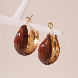 Macro shot of anchor red enamel teardrop earrings with elegant golden metal hooks