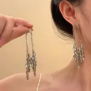Elegantes pendientes de borla de espiga dorados con brillantes hojas de metal en capas