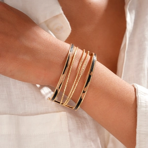 Dettaglio di un bracciale multistrato dorato con stampa leopardata indossato