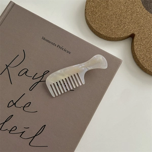 Pettine per capelli bianco perlato su libro d'epoca con sottobicchiere in sughero