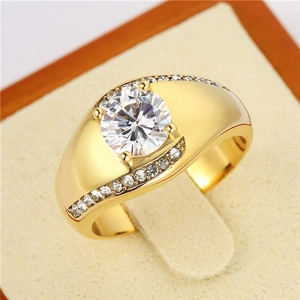 Macro d'une bague large dorée avec un grand zircon blanc et détails pavés brillants