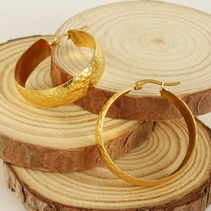 Macro detail of large 18K gold plated hoop earrings with hammered texture on wood
