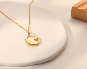 Gros plan sur le collier vintage doré avec pendentif soleil et lune en nacre blanche