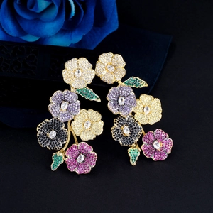 Close-up of golden flower earrings with colorful zircon stones on a dark background