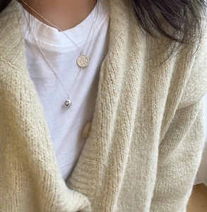 Close-up of layered 925 silver necklaces with smiley face and portrait coin pendants
