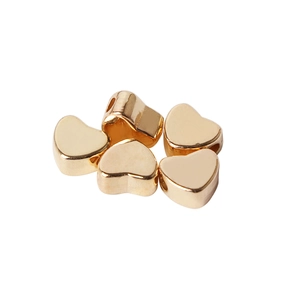Close-up van vijf glanzende gouden hartvormige kralen voor DIY-sieraden maken