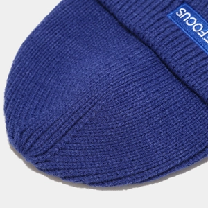 Detail of navy knit beanie showing focus letter label and ribbed texture weave