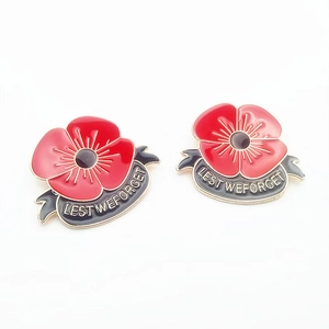 Détail de deux broches coquelicot en émail rouge avec gravure Lest We Forget dorée
