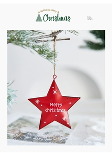 Macro shot of red metal star ornament with Merry Christmas print hanging on pine branch