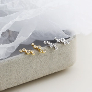 Detail of silver and gold bubble stud earrings with cubic zirconia on velvet box