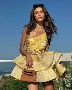 Detailed view of yellow floral one-shoulder dress with layered ruffles and waist cut-out