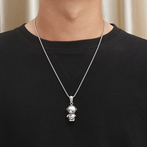 Close-up of a silver astronaut pendant with star detail on a steel chain worn by a model