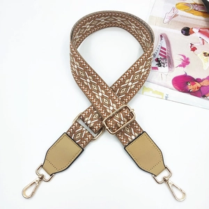 Close-up of geometric jacquard bag strap with leather ends and golden metal clips
