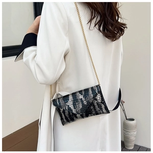 Close-up of black and white crocodile texture envelope bag with gold chain strap on model