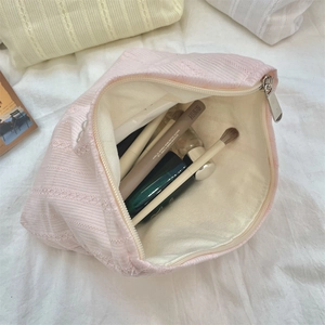 Detail view of pink bow cosmetic bag showing large interior capacity for makeup and brushes
