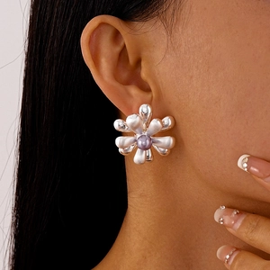 Gros plan sur une boucle d'oreille fleur argentée avec une perle de lavande délicate
