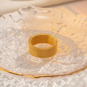 Detailed view of an 18K gold-plated stainless steel mesh ring on a glass tray