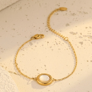 Gold oval chain bracelet with white mother of pearl inlay on minimalist background