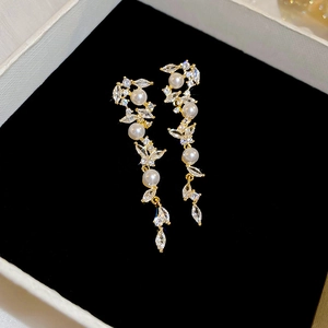 Macro view of gold-plated tassel earrings with white pearls and clear crystals on velvet