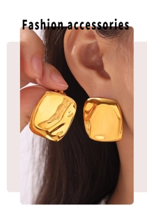Macro detail of large gold square earrings with hammered texture on earlobe