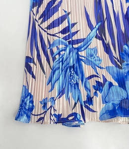 Macro detail of tropical floral print on pleated blue fabric with silky texture