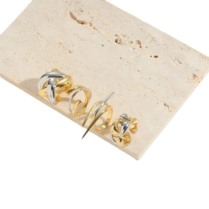 Abstract irregular open ring set in gold and silver finish on a stone platform