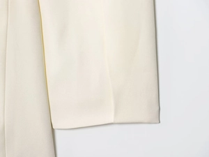 Close-up of cream white double-breasted blazer showing fine twill fabric and neat stitching
