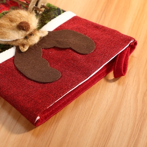 Red linen Christmas stocking with felt reindeer decoration on a wooden background