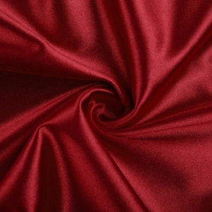 Gros plan sur un tissu en satin rouge foncé montrant une texture lisse et soyeuse