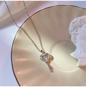 Vue détaillée d'un pendentif clé en argent avec diamants étincelants sur plateau céramique