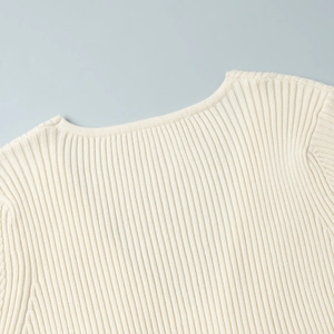 Close-up of the elegant V-neckline and ribbed knit texture on this cream-colored dress