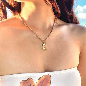 Collana dorata con ciondolo a stivale da cowboy e catena a corda su modella femminile