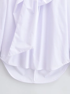 Detail of white long sleeve blouse featuring a bow tie front and curved hemline