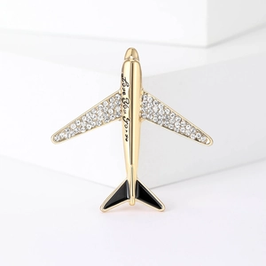 Golden airplane brooch with sparkling crystals and Love you more engraving on a white stand
