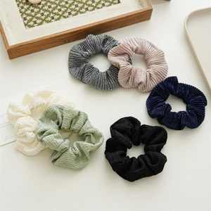 Detailed view of six assorted ruffled fabric scrunchies in various pastel and neutral colors
