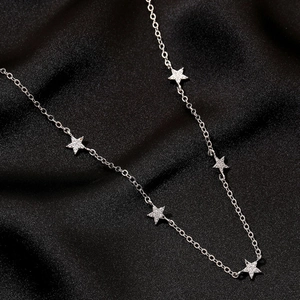 Dettaglio ravvicinato di una collana argento con cinque ciondoli a stella lucenti