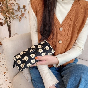 Detail of floral corduroy pencil case with secure zipper held by hand in a cozy setting