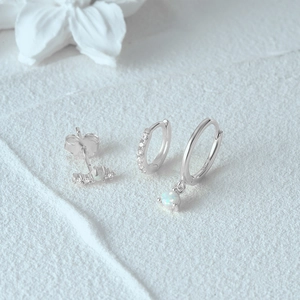 Detailed view of S925 sterling silver opal earrings with diamond accents on white flower