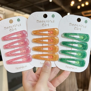 Sparkly triangular hair clips in pink, gold, and green on white cardstock