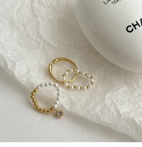 Détail du lot de bagues dorées avec perles blanches et pendentif en cristal