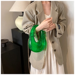 Detail of green transparent crescent bag with elegant gold chain strap and acrylic texture