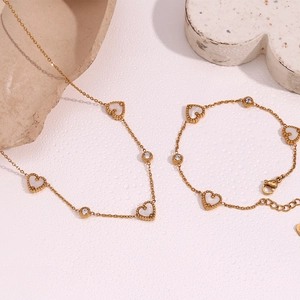 Close-up of 18K gold-plated heart-shaped necklace and bracelet with mother-of-pearl inlays