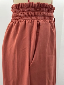 Détail de la taille haute d'un pantalon large rouge brique avec ceinture élastique froncée
